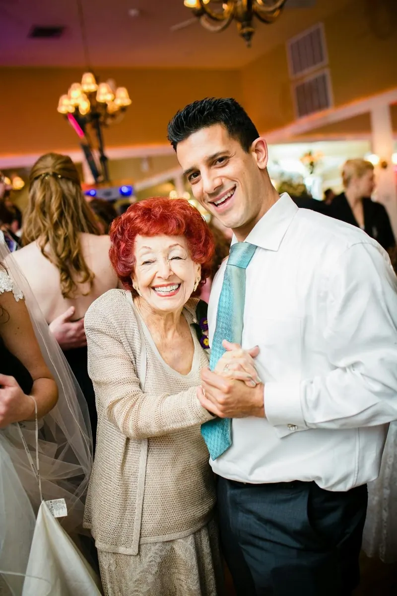 Une invitée âgée danse avec un jeune homme, tous deux hilares