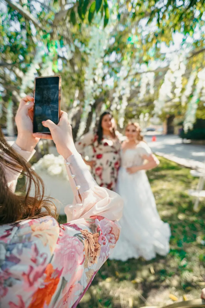 Une invitée photographie la mariée avec son téléphone