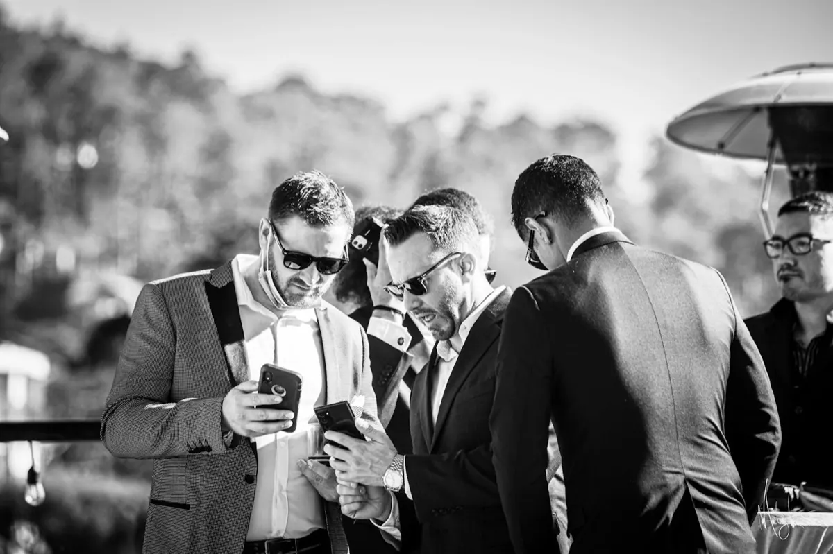 Des invités en costume regardent leurs téléphones